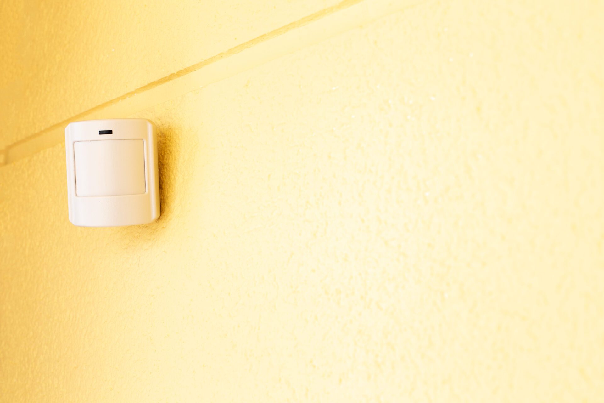 A motion sensor on a yellow wall.