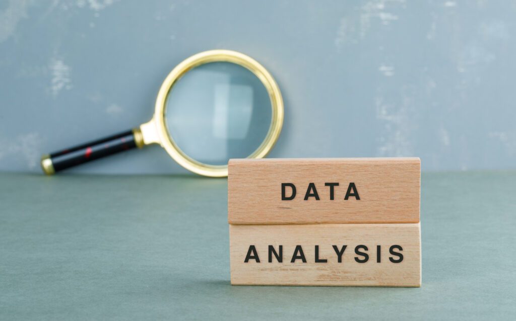 Wooden blocks with the words "data analysis" next to a magnifying glass